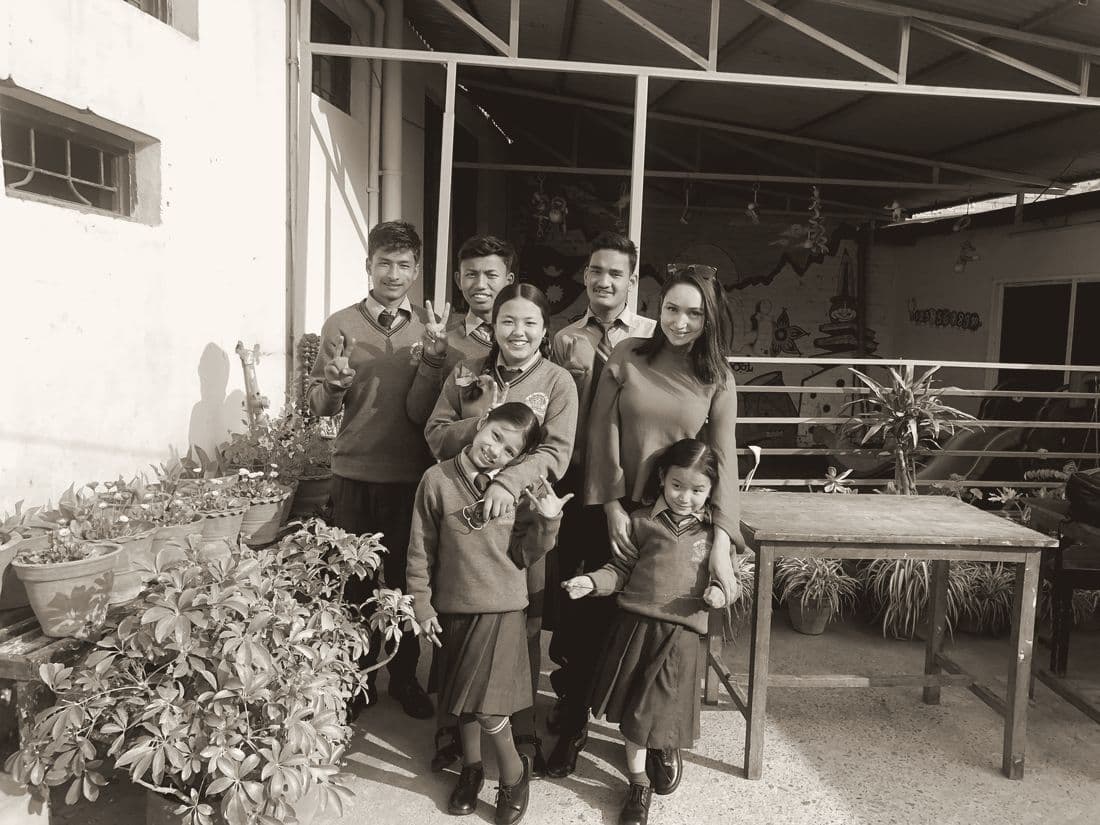 Pooja with students in school uniform in a courtyard